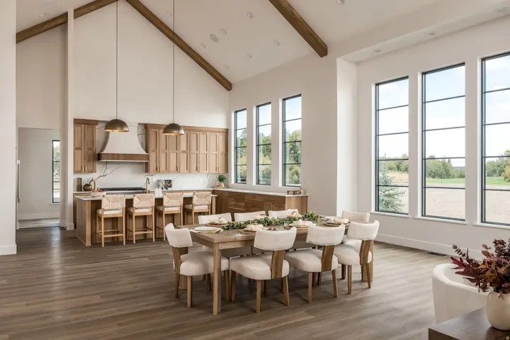 Vaulted ceiling with exposed wood beams, wood-finish flooring, full-height windows, kitchen island with seating, and wood cabinetry