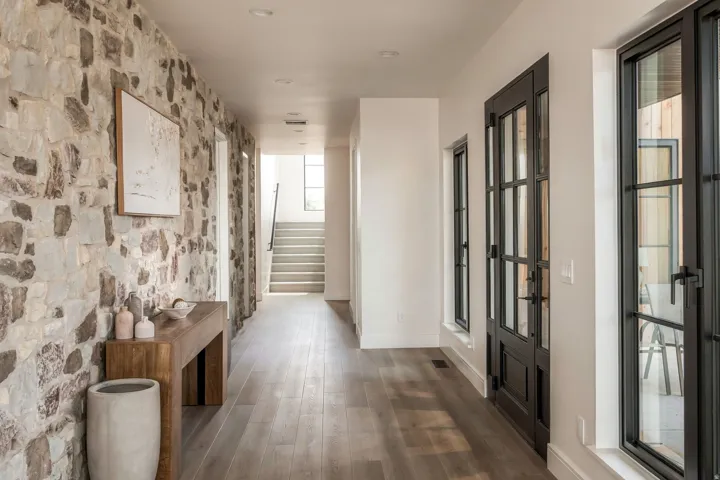 Hallway featuring a stone accent wall, wood-finish flooring, recessed lighting, and black-framed glass doors