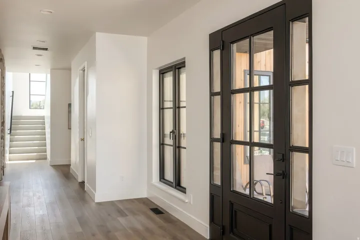 Glass-paneled entry door with sidelights, wood-finish flooring, and a stone accent wall
