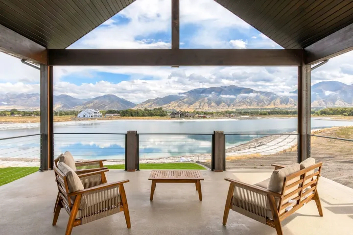Expansive covered patio with concrete flooring, vaulted ceiling, and cable railing system