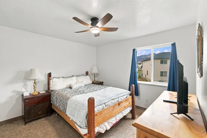 White walls, wood-finish flooring, a ceiling fan with integrated lighting, and a window with a mountain backdrop