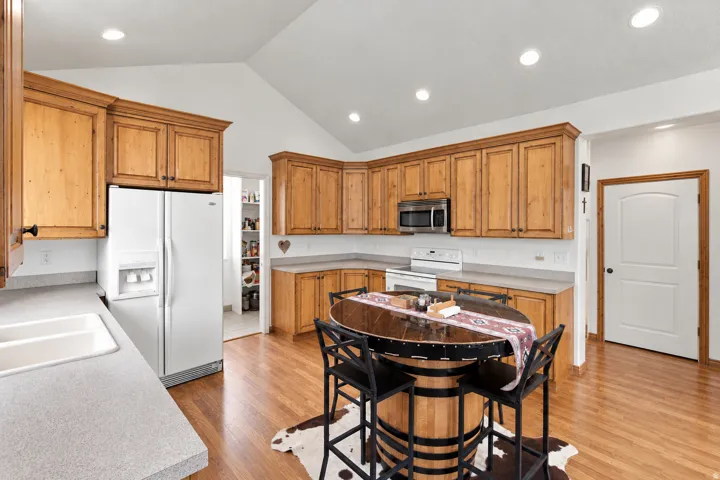 Vaulted ceiling, recessed lighting, wood-finish flooring, wood cabinetry, and a walk-in pantry