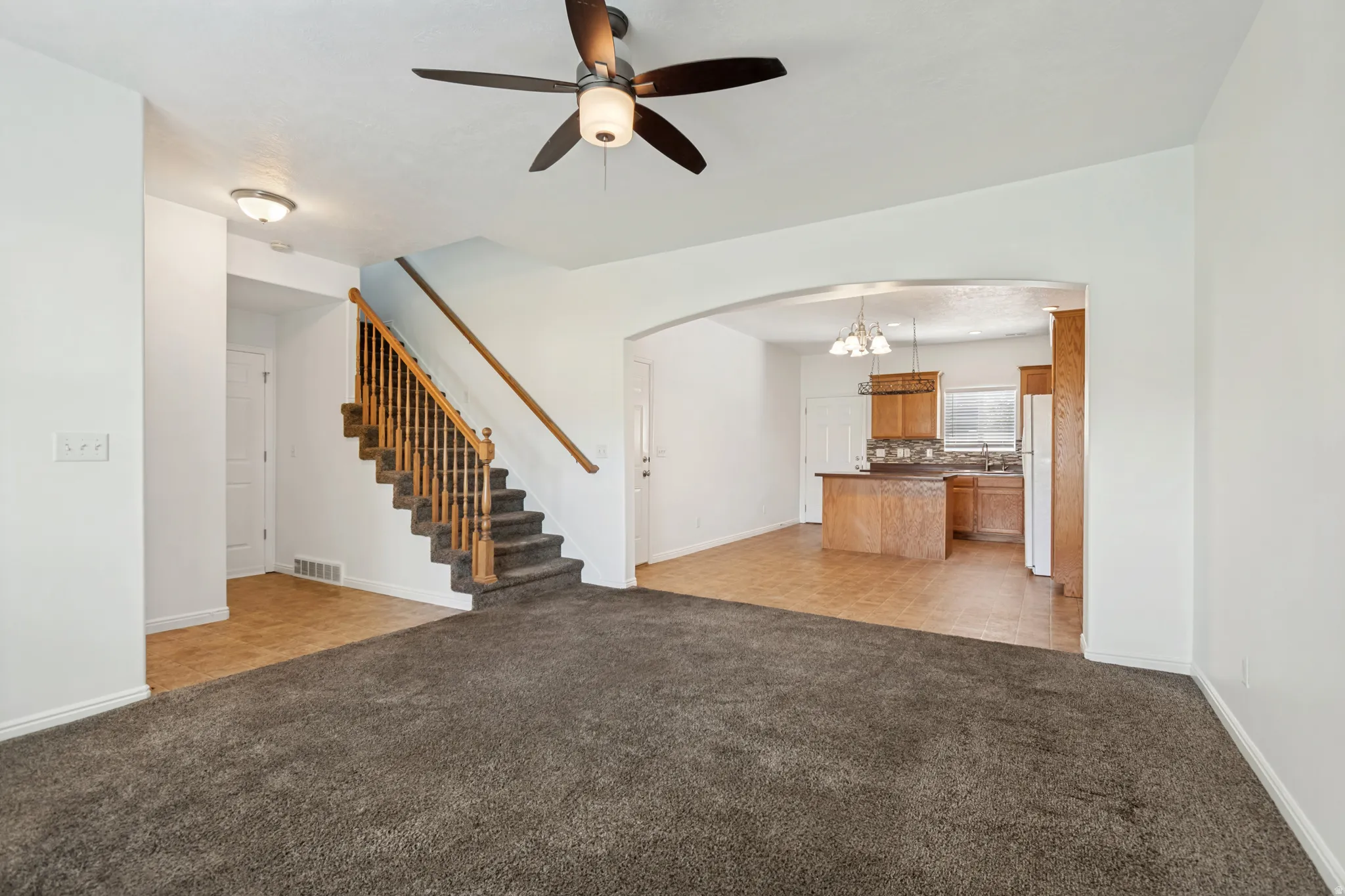 Living area featuring a ceiling fan, plush carpeting, and an arched entryway