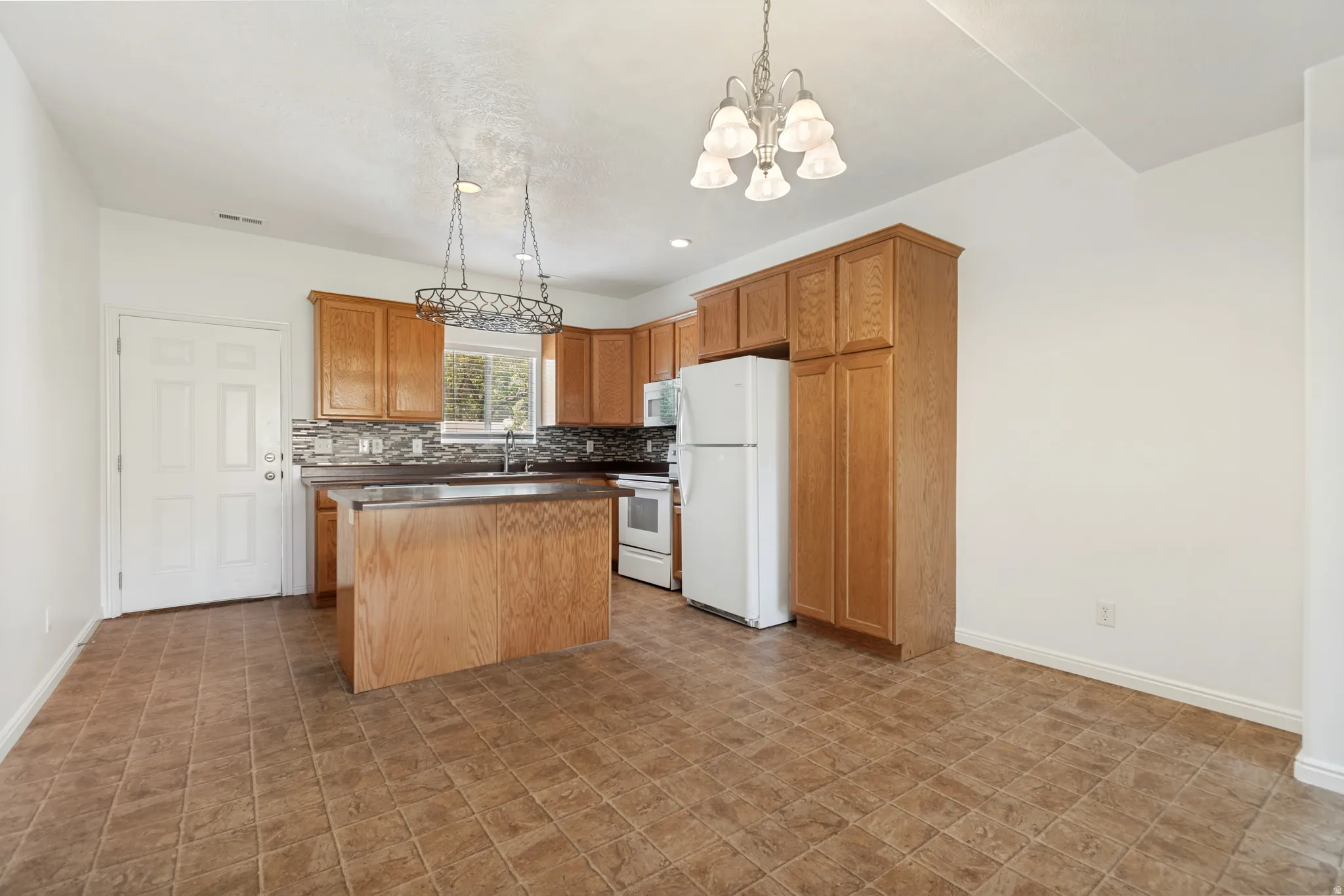 Kitchen featuring wood cabinetry, a center island with countertop, tile backsplash, and durable tile flooring