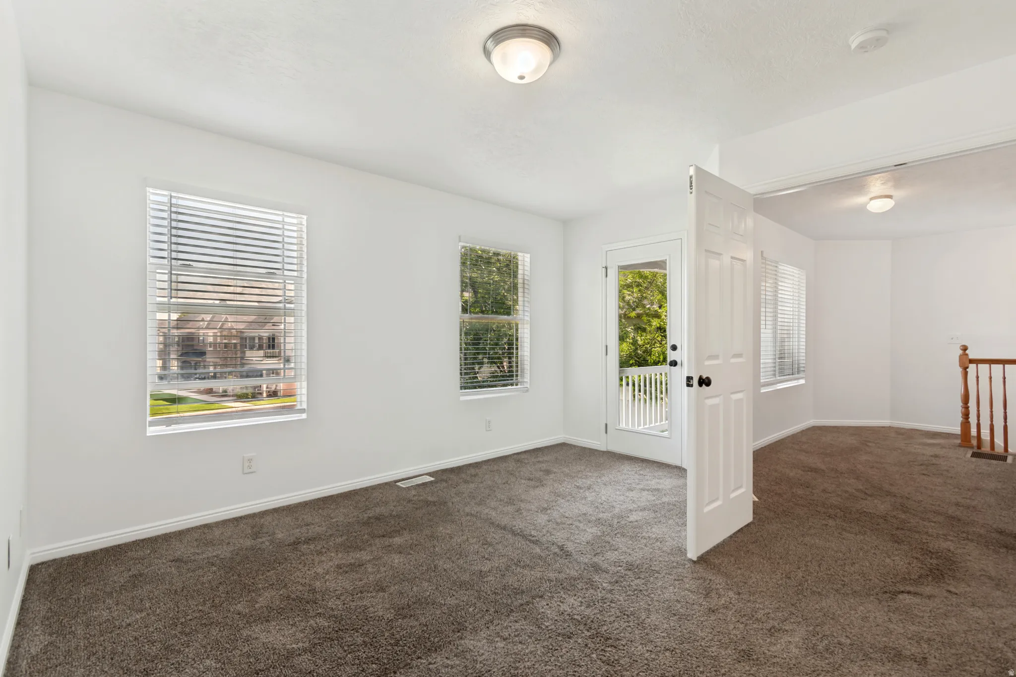 Wall-to-wall carpeting and white walls, with multiple windows featuring blinds