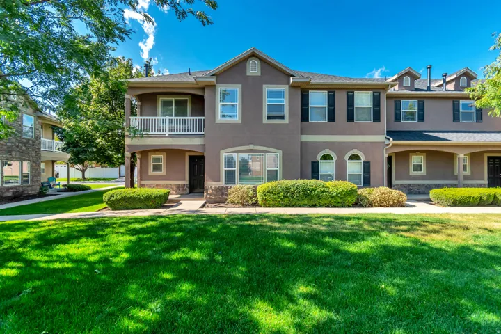 Stucco exterior with stone accents, a covered entry, an upper-level balcony, and decorative shutters