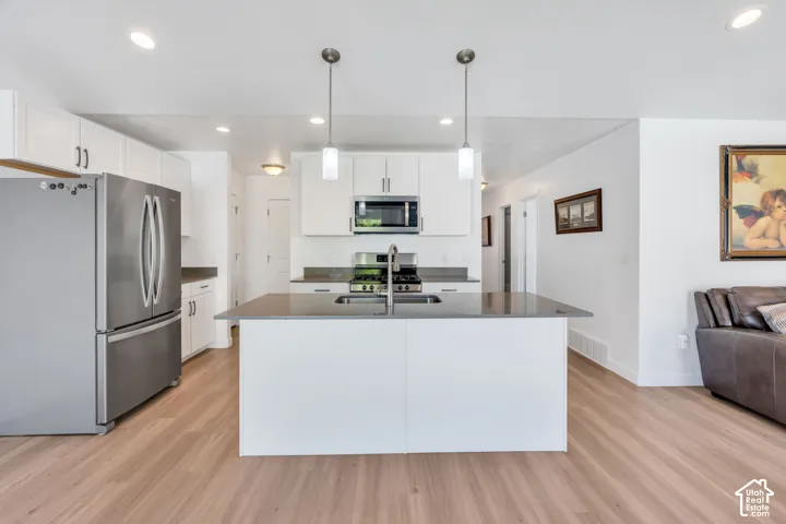 Open-concept kitchen with a large central island, like new white cabinetry, whirlpool fridge included.