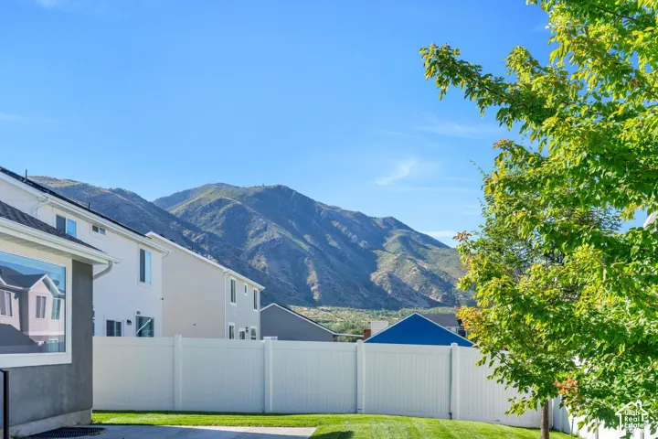Expansive backyard featuring a manicured lawn, white privacy fencing, and mountain views