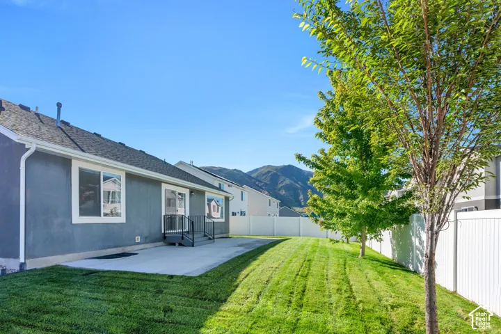 Backyard showing large patio, mature trees, fully fenced area.