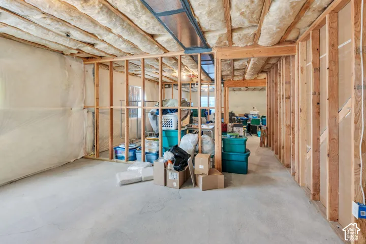 Unfinished basement space with exposed framing and insulation, concrete flooring, and visible structural beams