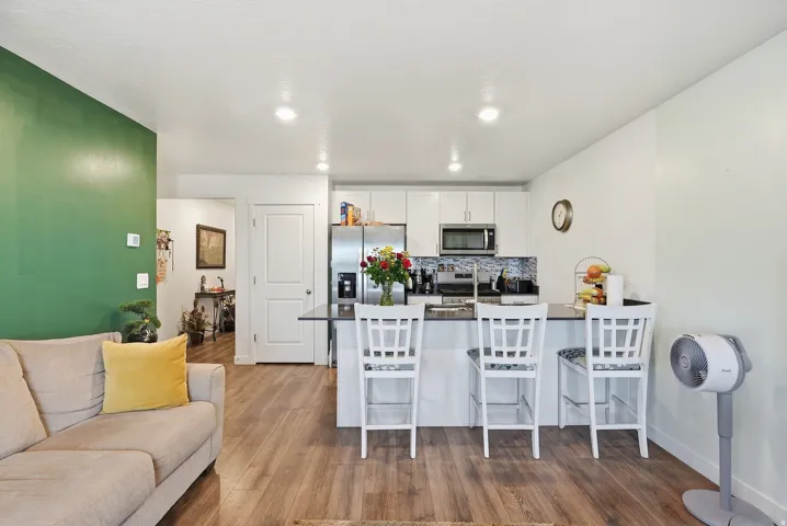 Open-concept living area with wood-finish flooring, recessed lighting, and a kitchen island featuring a breakfast bar