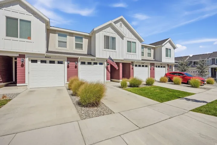 Townhome exterior featuring white siding, red paneling, and individual garages