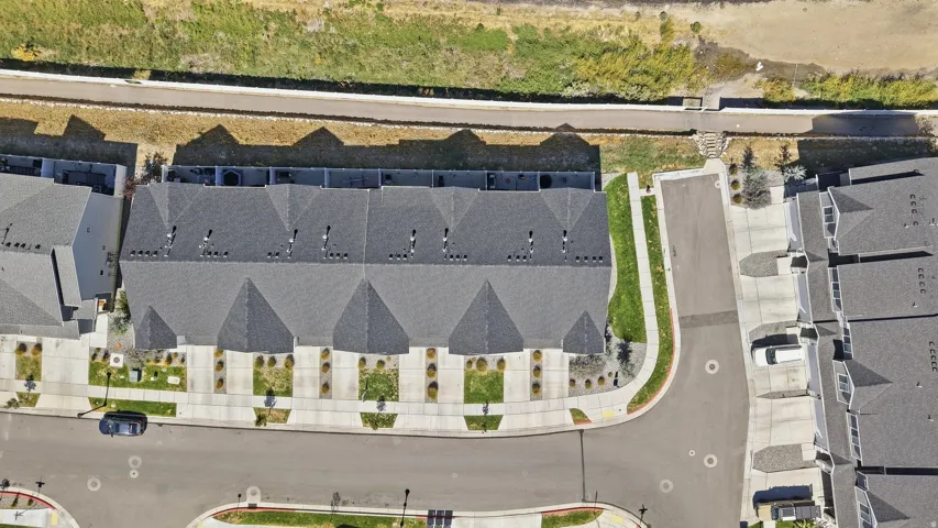 Townhome community featuring gray shingle roofs, paved roadways, and landscaped common areas