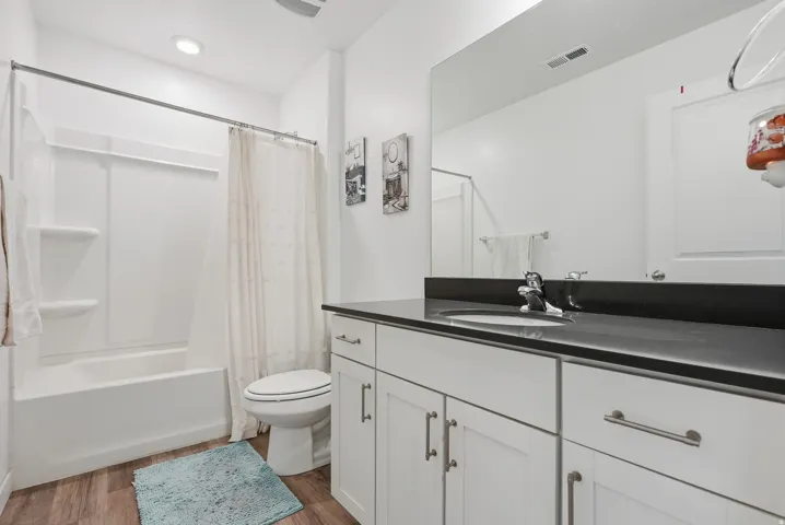 White vanity with brushed nickel hardware, integrated sink, and dark countertop