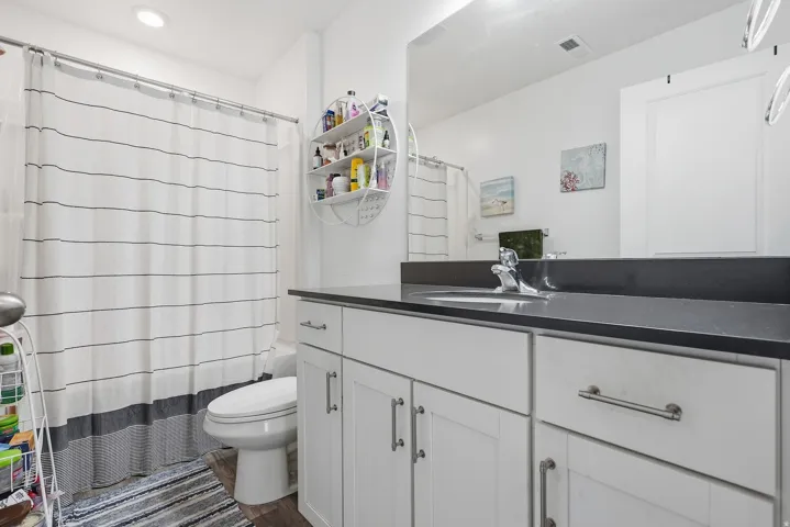 White vanity with brushed nickel hardware, dark countertop, and an integrated sink with a chrome faucet