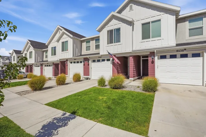 Modern townhome-style residences featuring board and batten siding, attached garages, and paved driveways