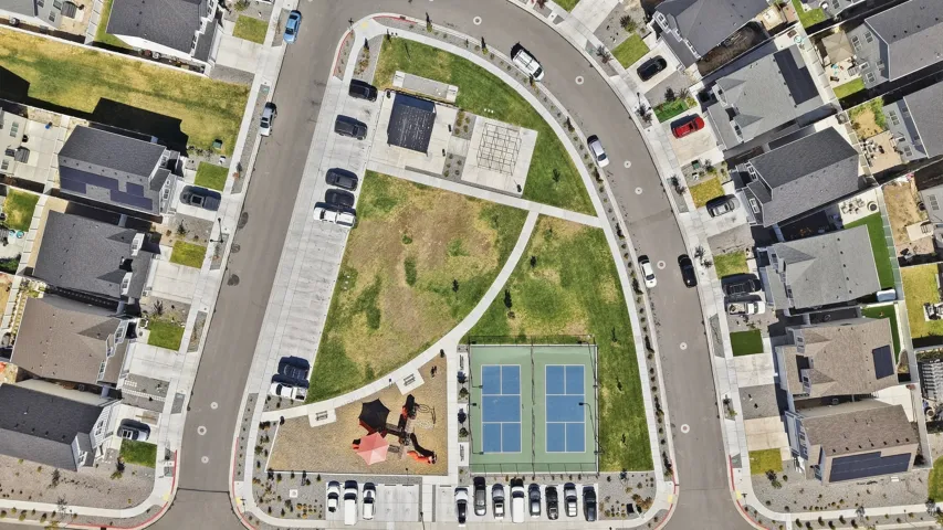 Community green space featuring a tennis court, playground, and paved walking paths