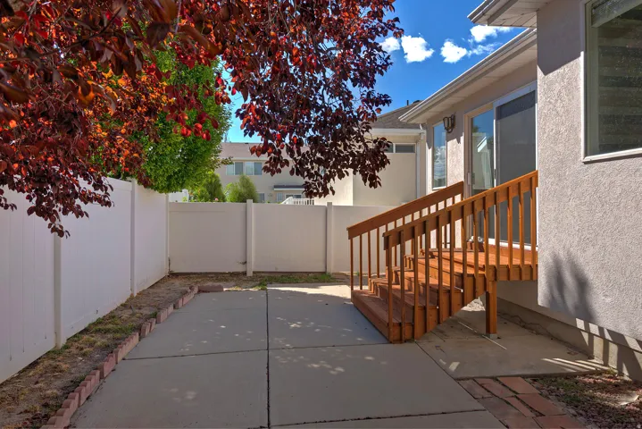 Private backyard featuring a concrete patio, wood deck with stairs, sliding glass door, and vinyl fencing
