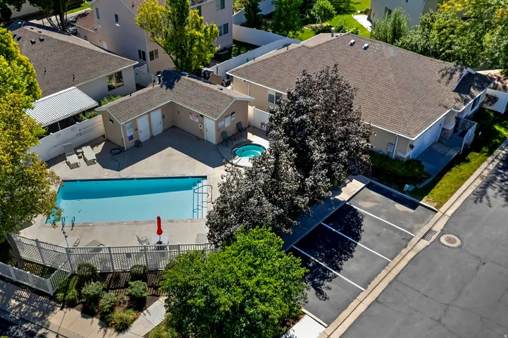 Community swimming pool with surrounding patio, integrated hot tub, and fenced perimeter