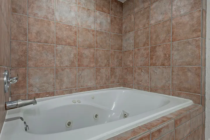 Built-in jetted tub with tile surround and wall-mounted fixtures