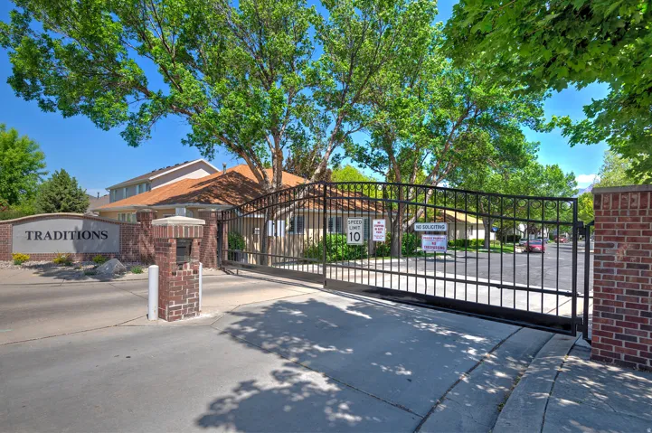 Gated entry featuring brick pillars, an arched iron gate, and a stone-clad monument sign