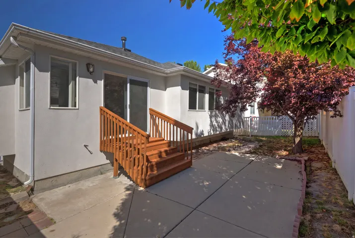 Rear exterior with a concrete patio, wooden staircase, and sliding glass door