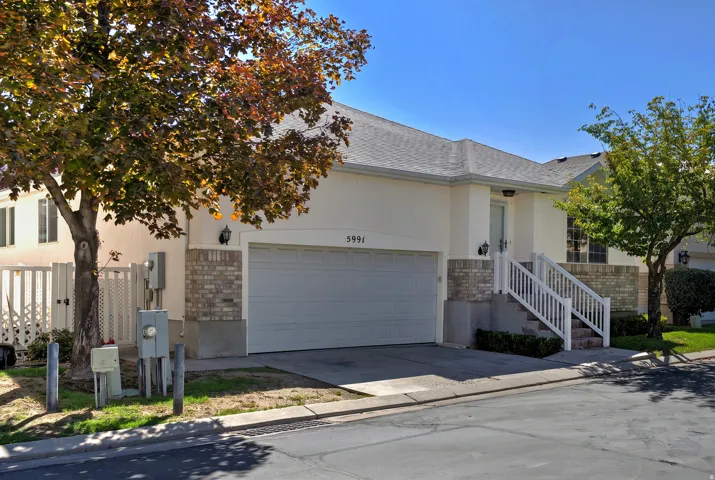Stucco exterior with a brick accent facade, attached two-car garage, and a covered entry with white railings