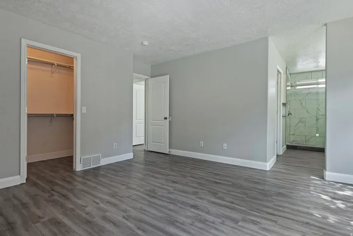Wood-finish flooring with light gray walls, an open closet, and a white interior door