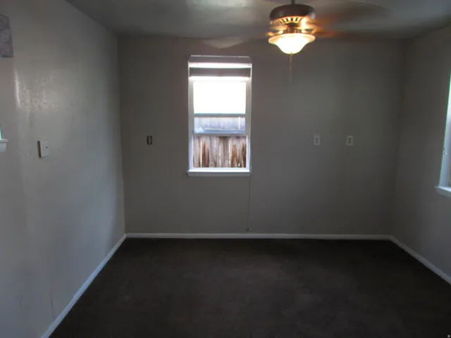 Recessed window with white trim, dark carpeting, and a ceiling fan with integrated lighting
