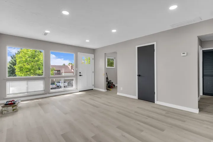 Recessed lighting, light wood-finish flooring, multiple windows, white entry door with glass inserts, and modern dark interior doors