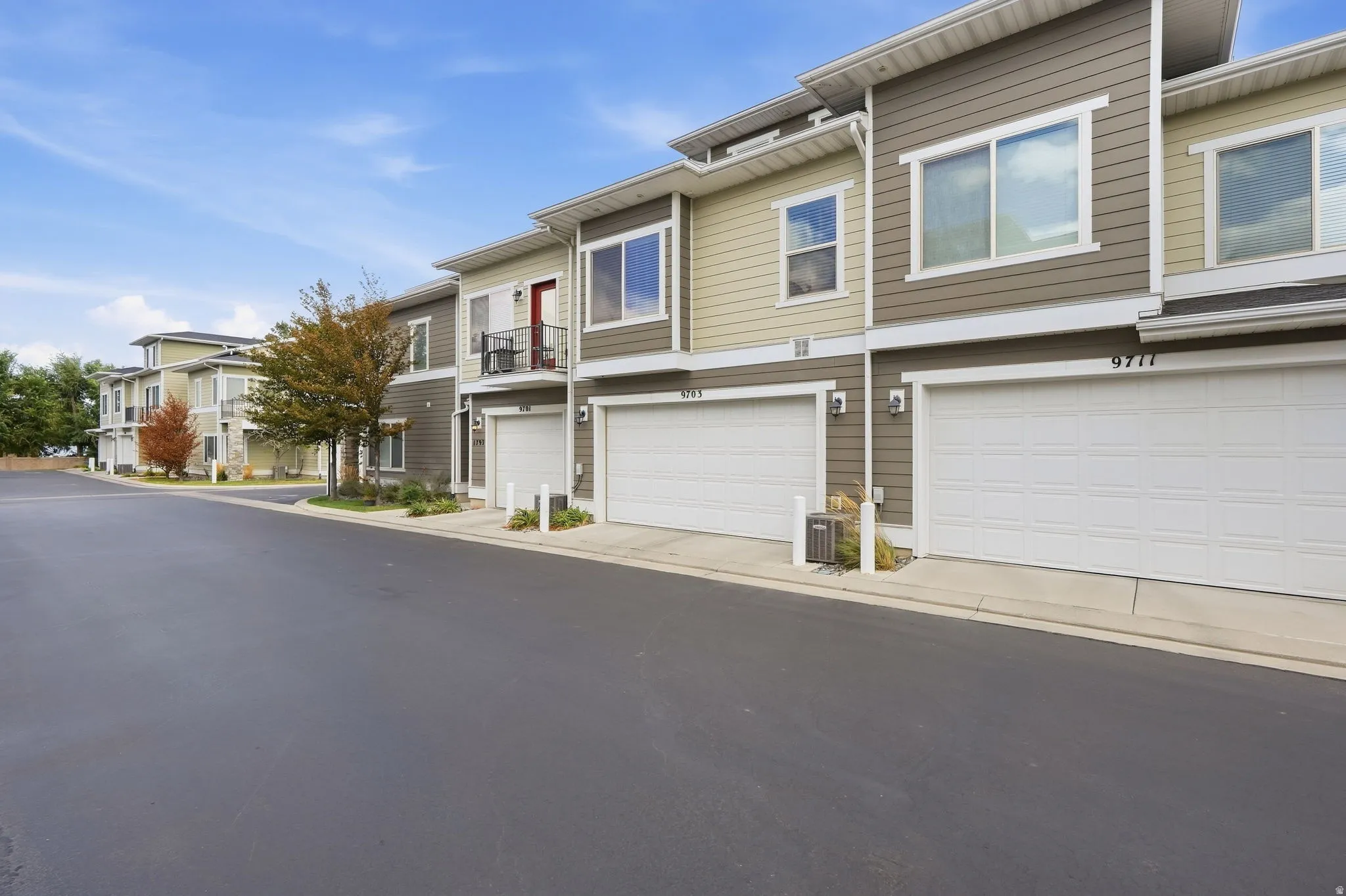Modern townhome-style residences featuring multi-tone siding, individual garages, and private balconies with metal railings