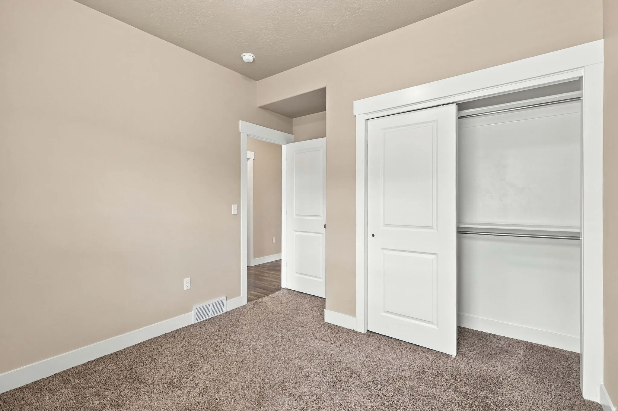 Carpeted room with neutral wall tones, white trim, and a white sliding closet door