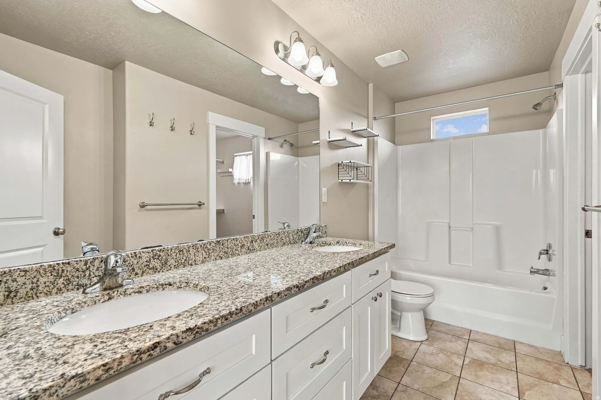 Dual vanity with granite countertop, white cabinetry, and undermount sinks