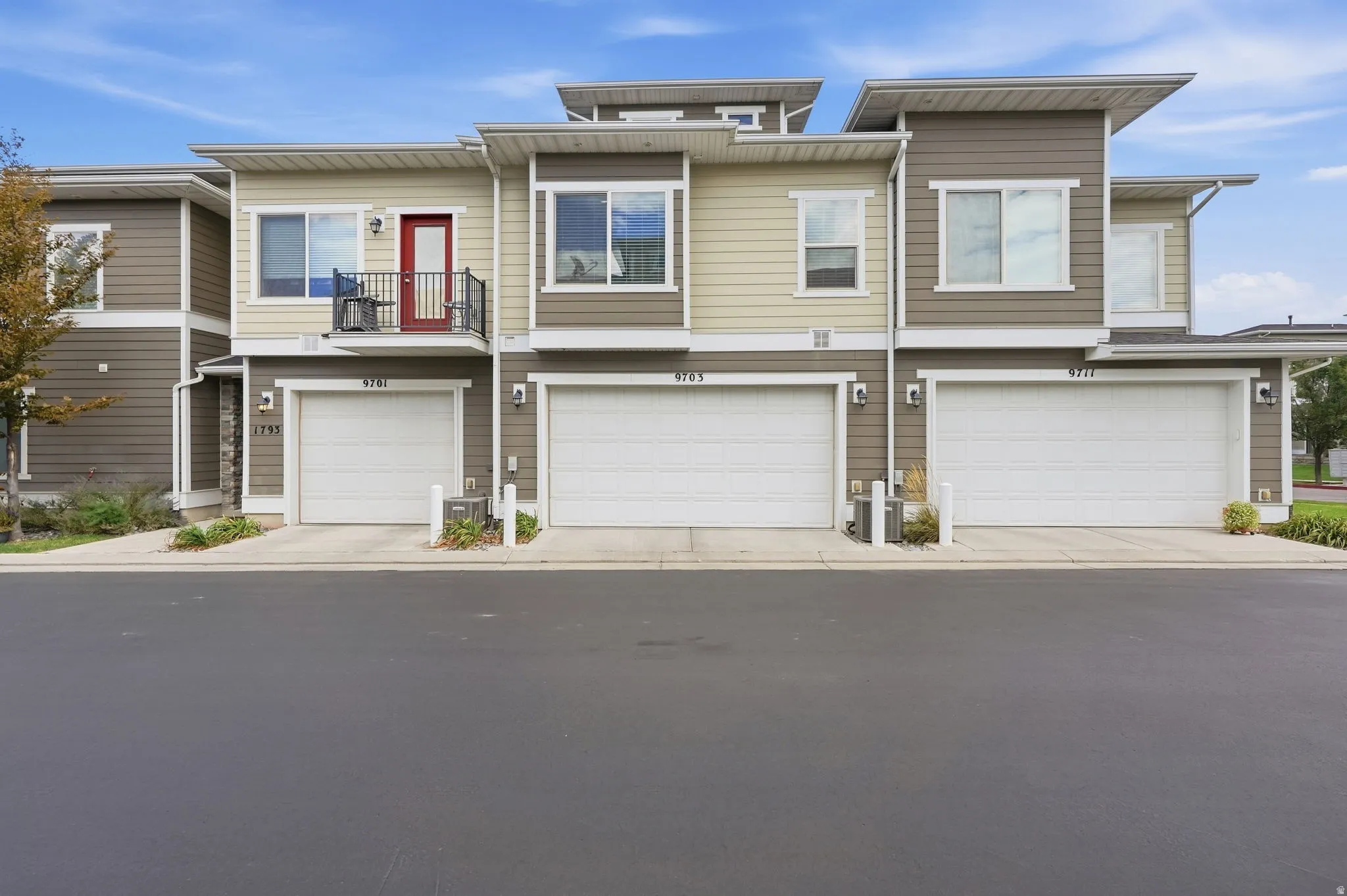 Multi-story contemporary exterior with a two-tone facade, white garage doors, and individual balconies with black railings