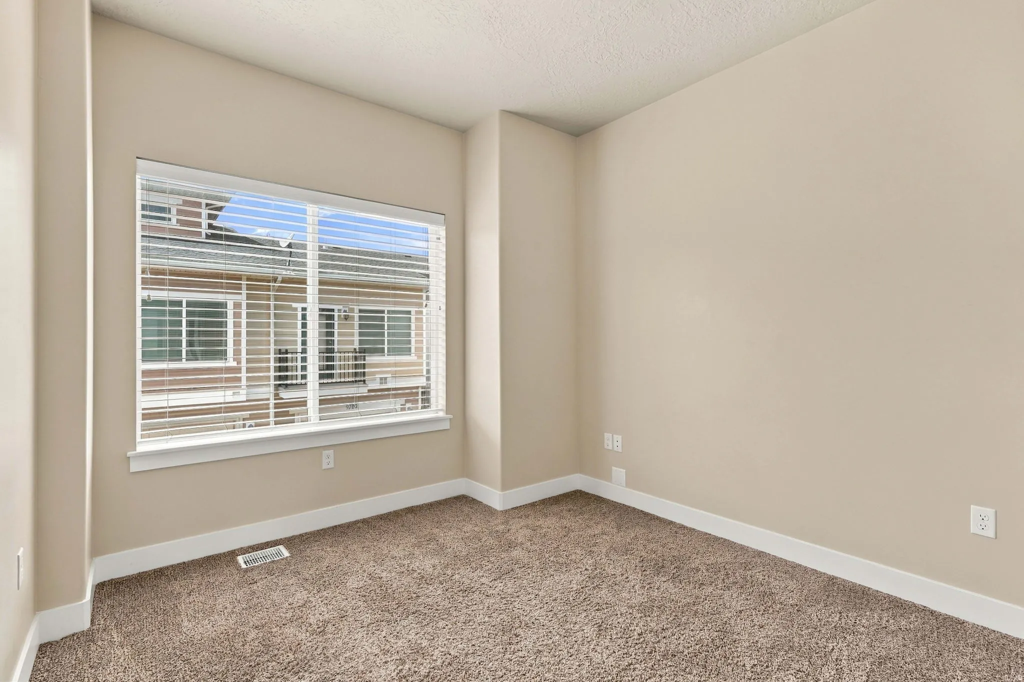 Neutral wall finishes, textured carpeting, a large window, and white trim