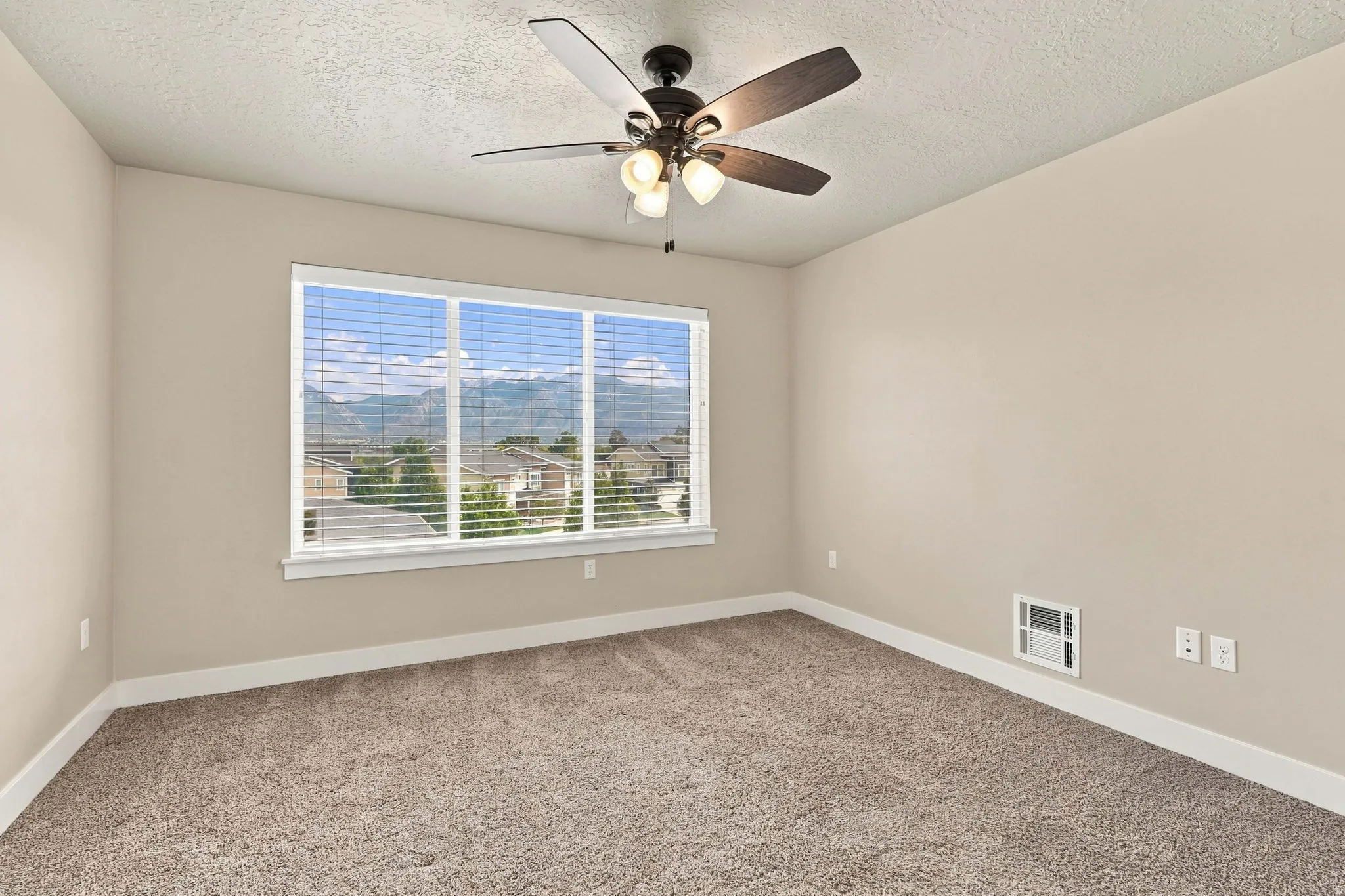 Spacious room featuring carpet flooring, a ceiling fan with integrated lighting, and a large window with white blinds