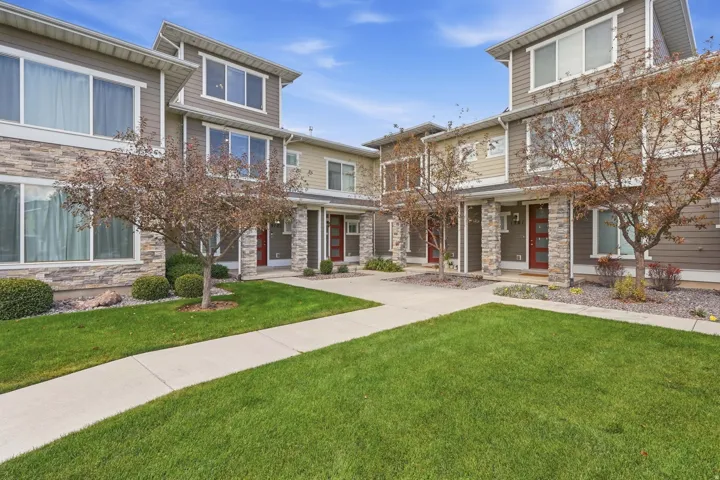 Contemporary townhome architecture featuring stacked stone accents, horizontal siding, multiple large windows, and a vibrant red entry door
