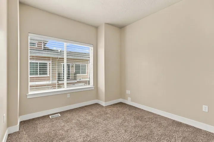 Neutral wall finishes, textured carpeting, a large window, and white trim
