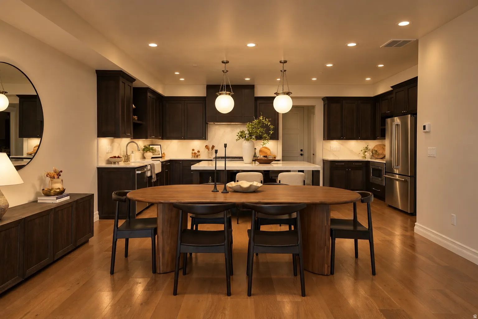 Open-concept kitchen featuring dark wood cabinetry, light wood-finish flooring, recessed lighting, and an expansive kitchen island with a built-in sink