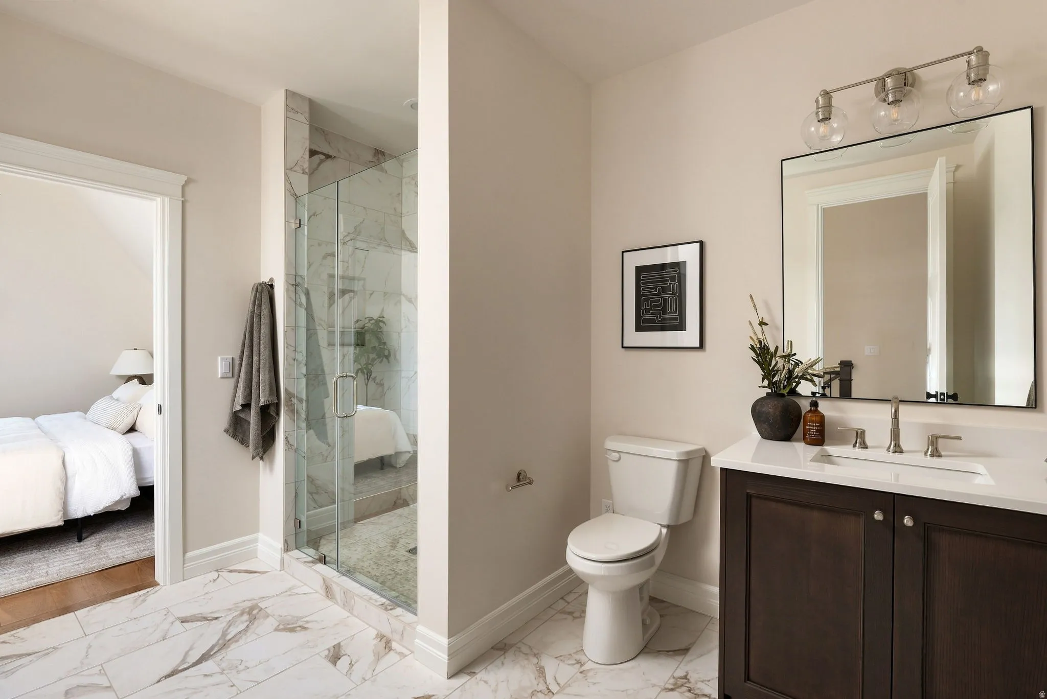 Walk-in shower with clear glass enclosure and marble-look tile surround