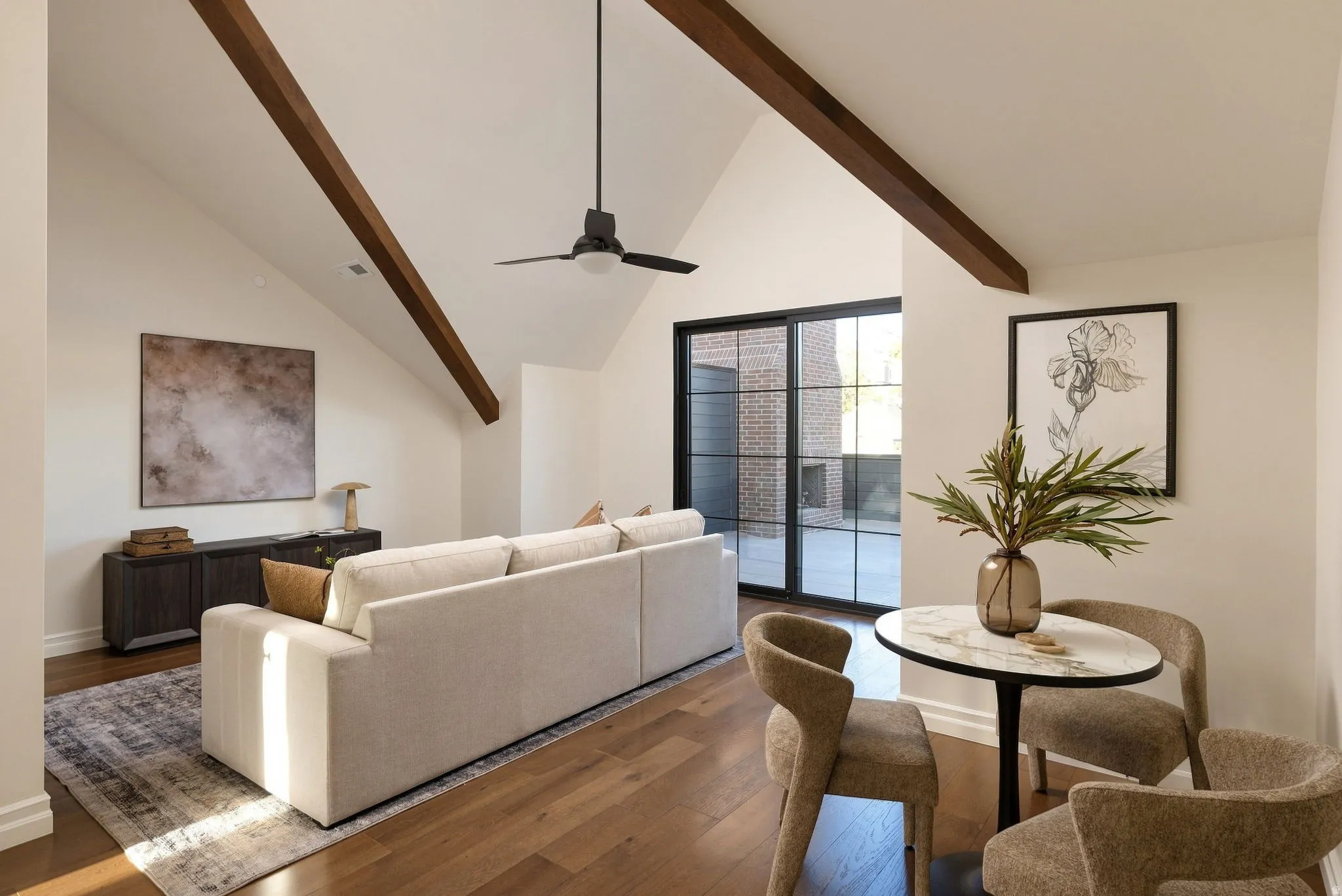 Vaulted ceiling with exposed wood beams, wood-finish flooring, built-in cabinetry, and sliding glass doors with black frames