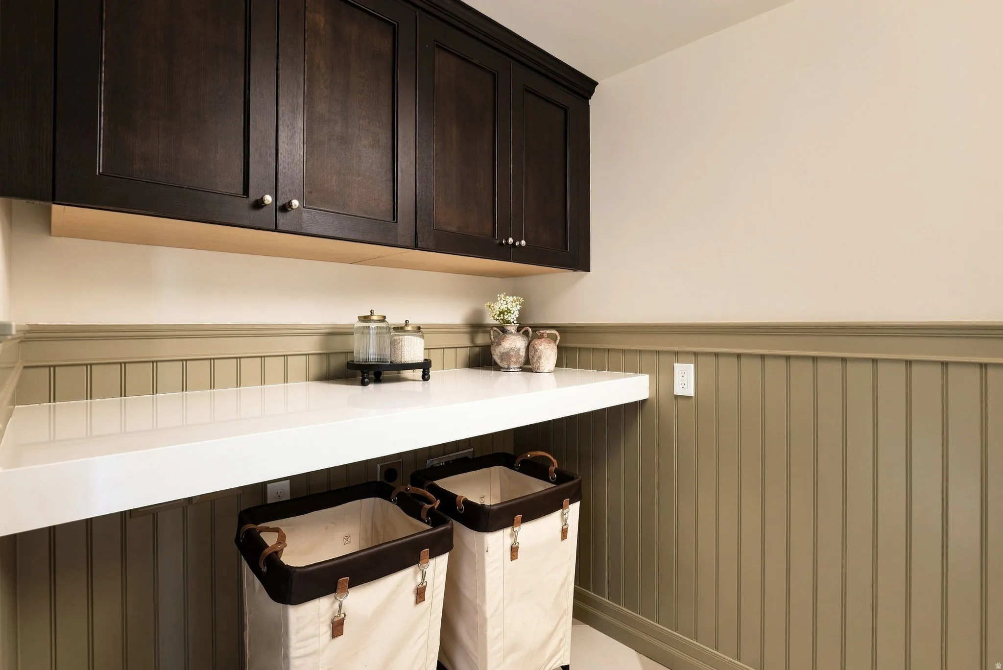 Dark wood-finish cabinetry, white countertop, beadboard wall paneling, and light-toned walls