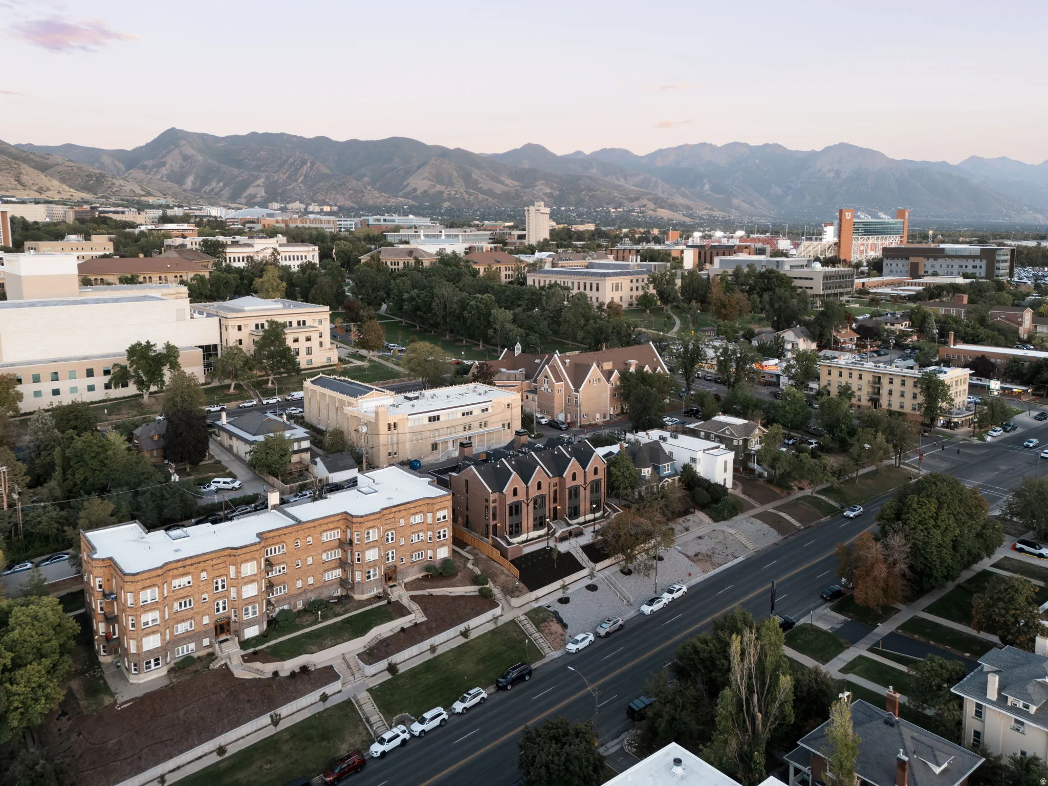 Urban setting with diverse architectural styles, tree-lined streets, and distant mountain ranges