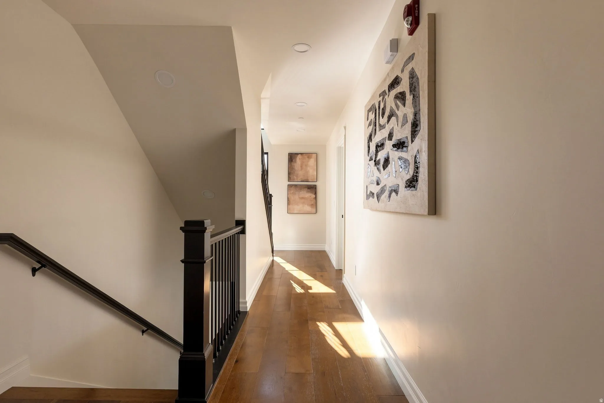 Hardwood flooring, recessed lighting, and a dark wood banister