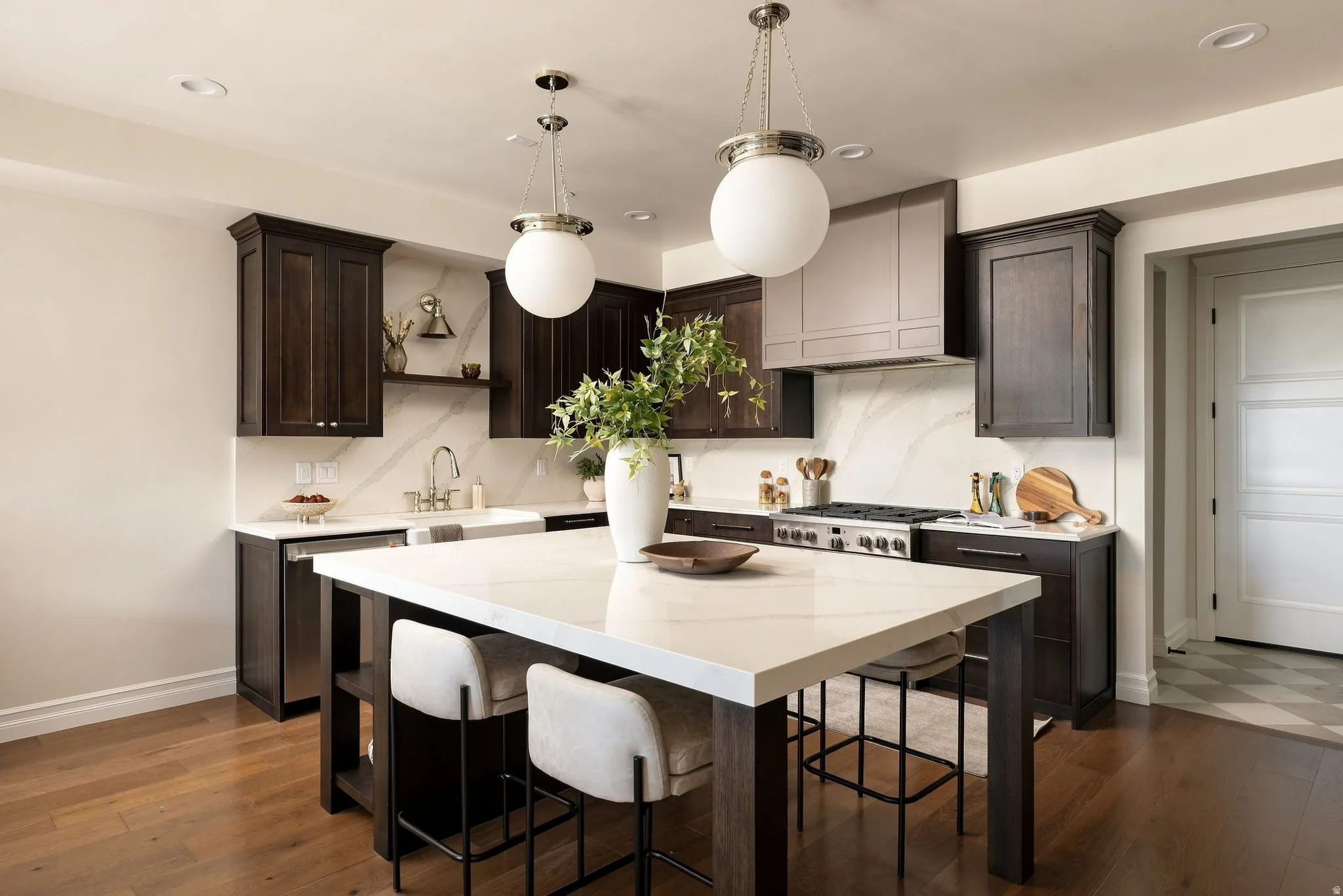 Gourmet kitchen with dark wood cabinetry, white countertops, a large center island, stainless steel appliances, and wood-finish flooring