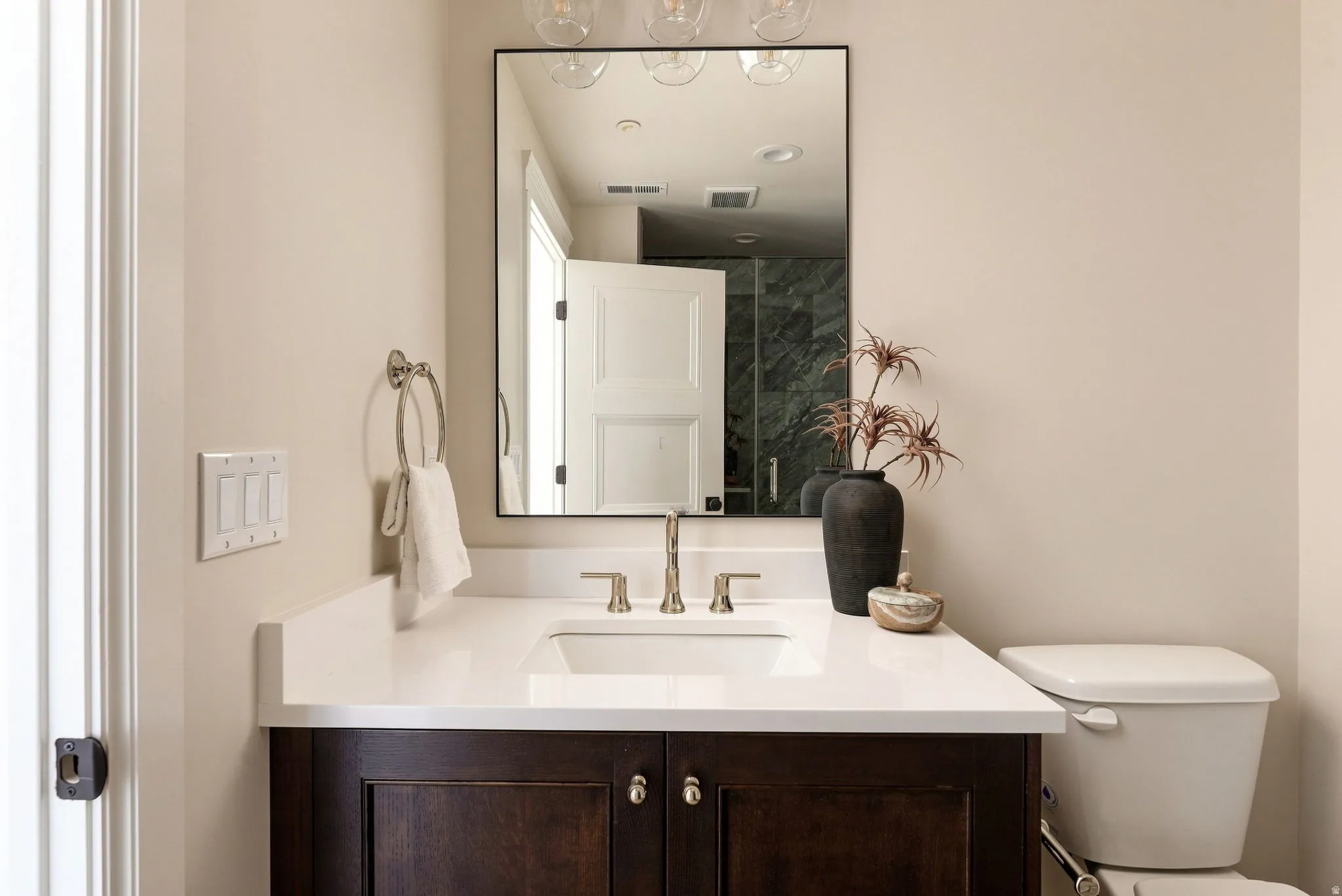 Bathroom featuring a dark wood-finish vanity, white countertop, undermount sink, and a framed mirror