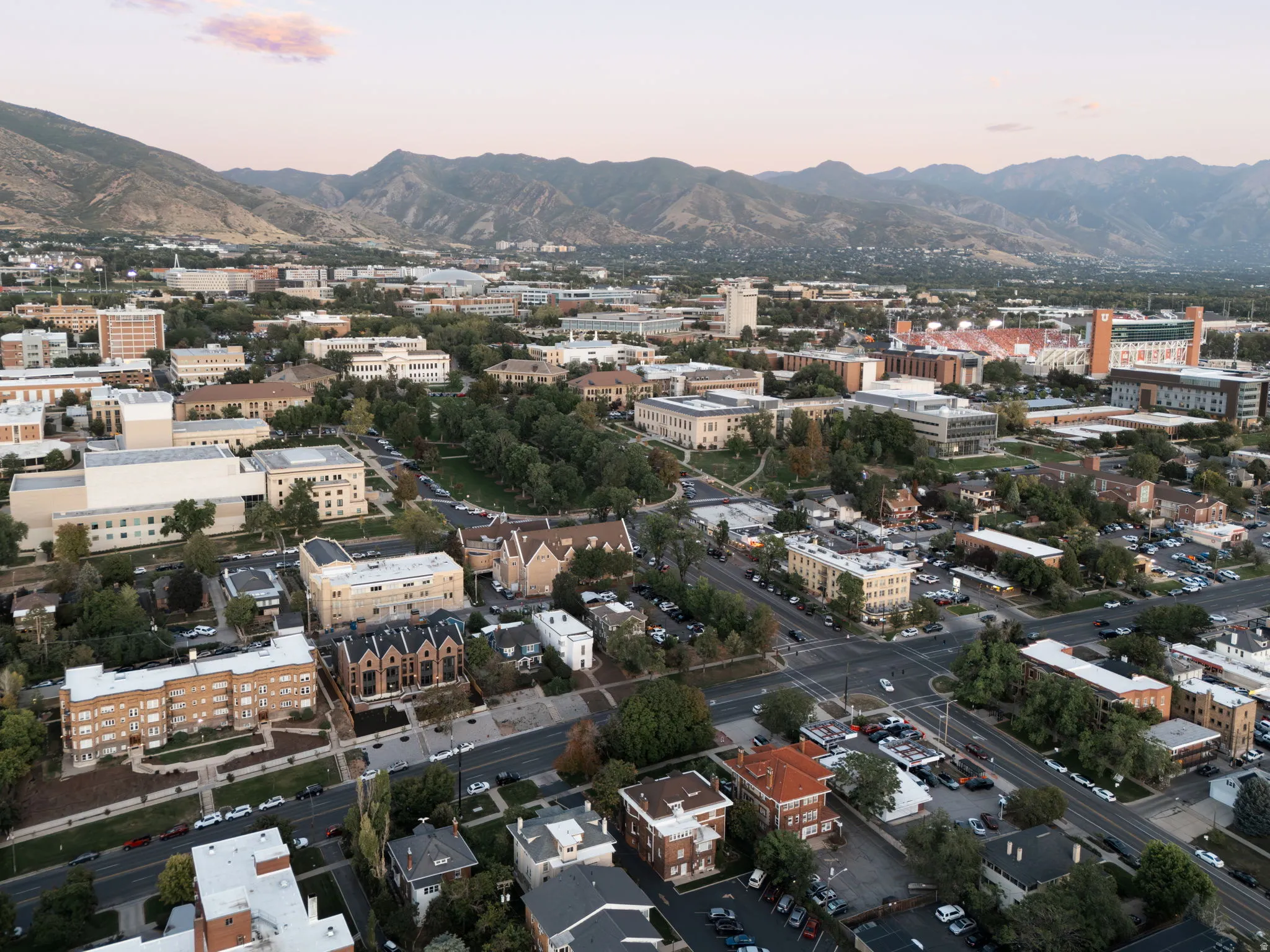 Aerial perspective showcasing a diverse urban landscape with prominent institutional buildings, extensive green spaces, and a mountainous backdrop