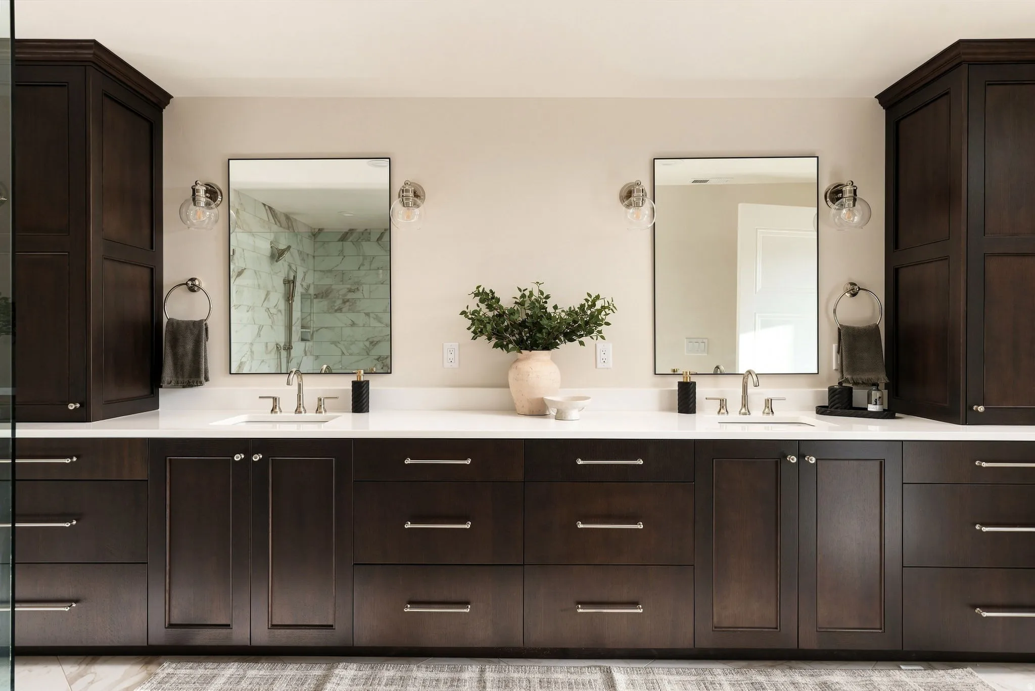 Dual vanity with dark wood-finish cabinetry, white countertops, two framed mirrors, and brushed nickel hardware