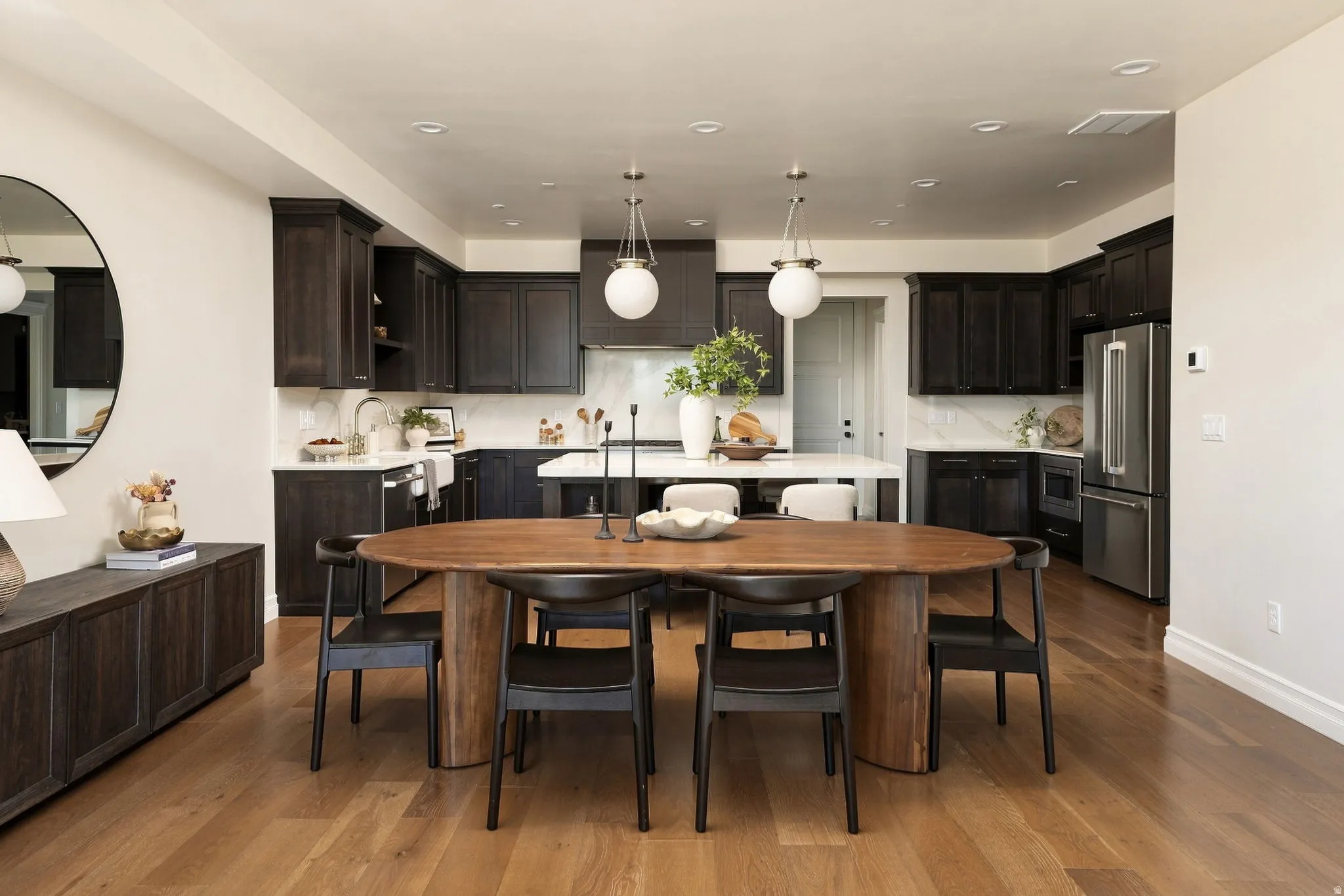 Kitchen featuring dark wood-finish cabinetry, stainless steel appliances, white countertops with a matching backsplash, and a central island with pendant lighting