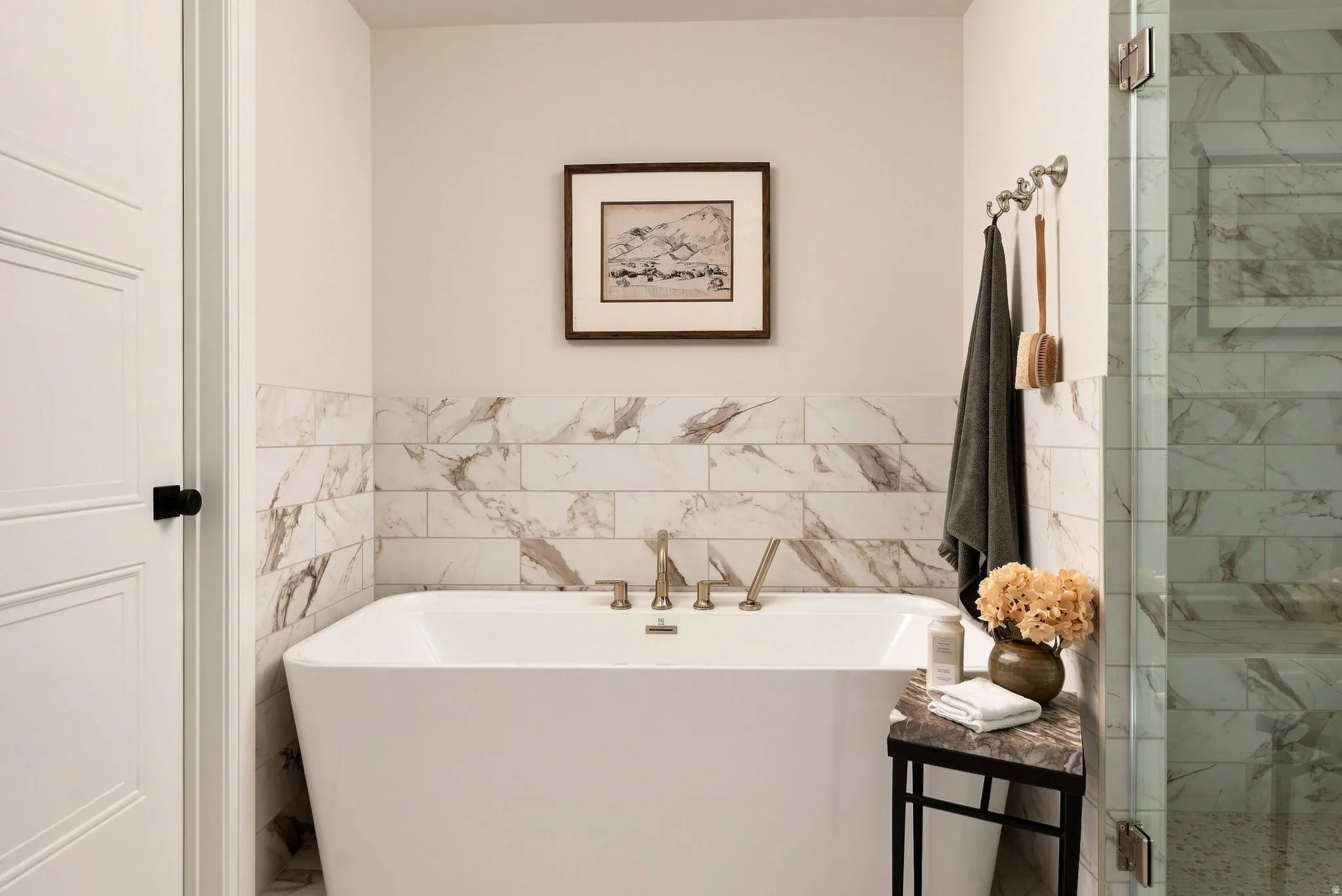 Freestanding soaking tub with brushed nickel fixtures, subway tile surround with natural stone veining, and a glass-enclosed shower with matching tile